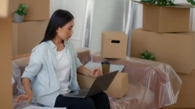 Dizüstü bilgisayarda iç dizayn yapan Çinli kadın içeride kahve içiyor.