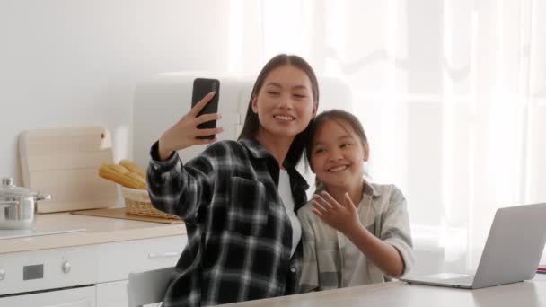 Madre e hija chinas haciendo selfie en el teléfono en la cocina — Vídeo de stock