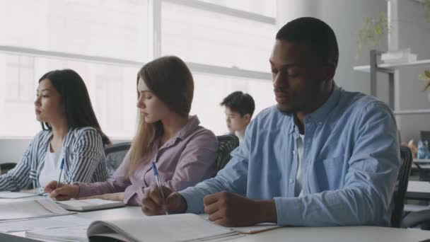 Programa de educação internacional. Grupo de estudantes universitários diversos tarefa de escrita durante a aula em sala de aula — Vídeo de Stock