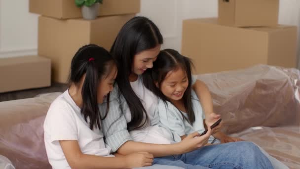 Mãe coreana e filhas usando smartphone entre caixas móveis interior — Vídeo de Stock