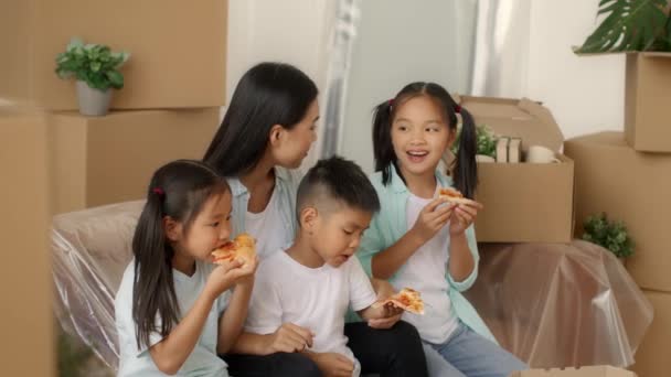 Ασιατική οικογένεια τρώει πίτσα κουτιά συσκευασίας κινείται νέο σπίτι εσωτερική — Αρχείο Βίντεο