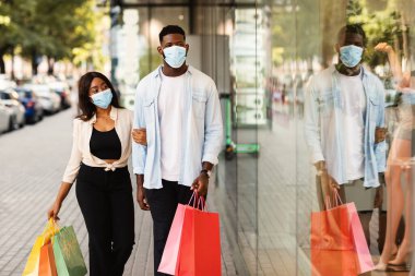 Alışveriş çantalı mutlu siyah çift portresi.