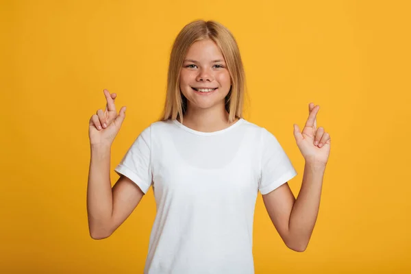 Sorrindo jovem caucasiana estudante feminina em t-shirt branca cruzou os dedos e faz um desejo — Fotografia de Stock