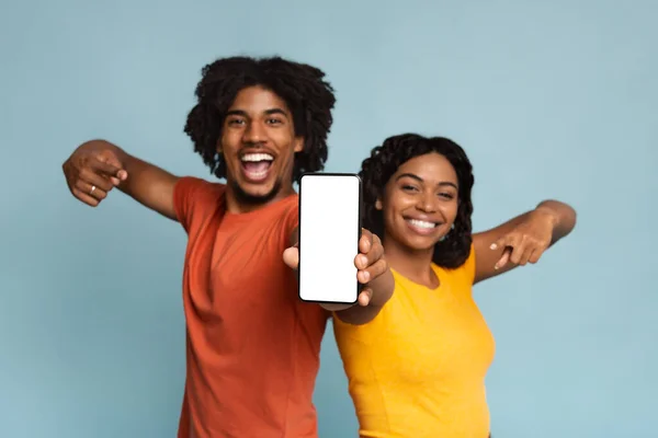 Gelukkig afro-Amerikaanse millennials wijzen naar mobiele telefoon met lege display — Stockfoto