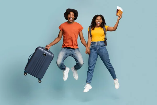 Opgewonden afro-amerikaanse paar gaan vakantie samen, blauwe studio achtergrond — Stockfoto