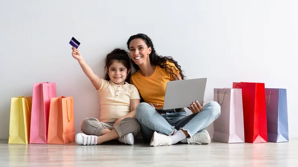 Madre e hija árabes posando con laptop, tarjeta de crédito y bolsas de compras —  Fotos de Stock