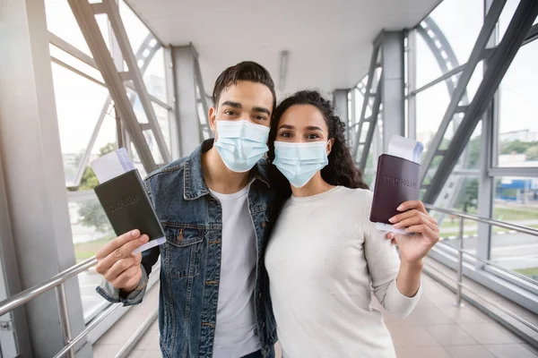 Los cónyuges árabes en máscaras médicas posando con pasaportes y boletos en el aeropuerto —  Fotos de Stock
