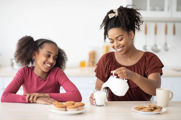 Bastante negro madre verter fresco leche para su adolescente hija — Foto de Stock