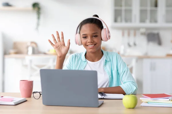 Pensativo adolescente afroamericano chica estudiante estudio en casa con el ordenador portátil, llamando en línea y saludando de la mano —  Fotos de Stock