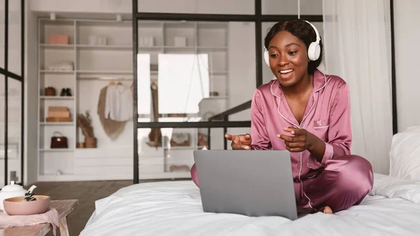 Schwarze Frau macht Videoanruf auf Laptop und trägt Kopfhörer im Haus — Stockfoto