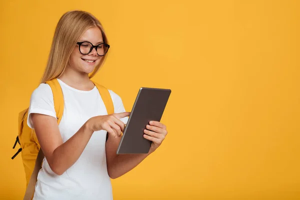 Usmívající se dospívající běloška v bílém tričku, brýle s batohem studie s tabletou — Stock fotografie