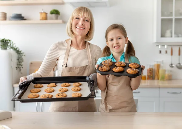 Счастливая пожилая женщина и ее внучка пекут печенье — стоковое фото