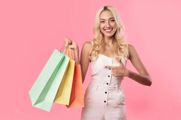 Mulher sorridente segurando apontando para sacos de compras no estúdio — Fotografia de Stock