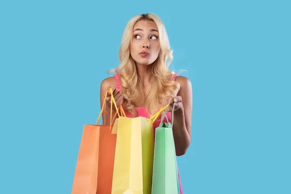 Pensive mulher segurando sacos de compras coloridos olhando para longe — Fotografia de Stock