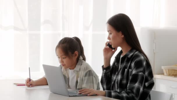 Asiatique mère parler sur téléphone travail assis avec fille intérieur — Video