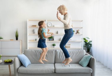 Pozitif büyükanne kucağında torunuyla kanepeye atlıyor.