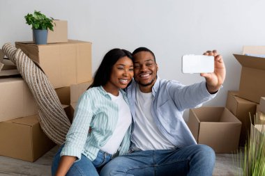 Yer değiştirme ve mülkiyet kavramı. Mutlu genç siyah çift kendi evine taşındıktan sonra selfie çekiyor.