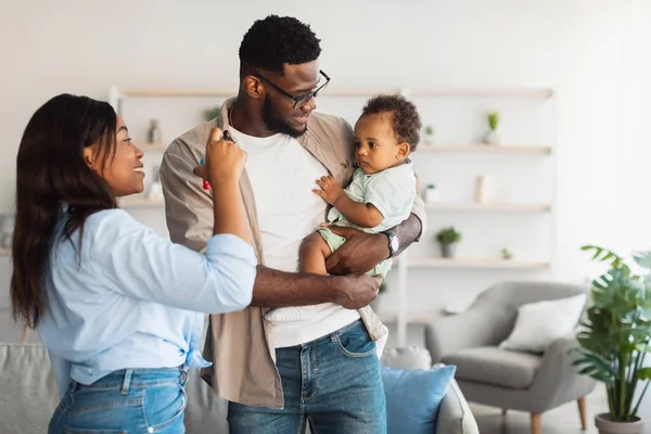 Gelukkig zwart ouders houden baby wijzen naar venster — Stockfoto