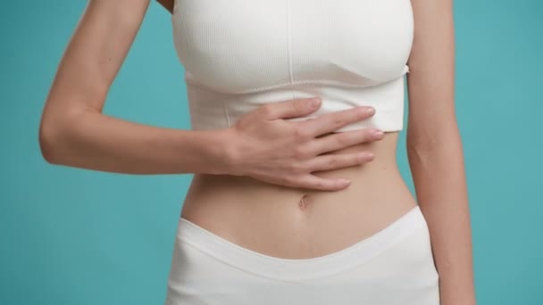 Nerozpoznatelná žena masáže břicho utrpení od bolesti břicha na modrém pozadí — Stock video