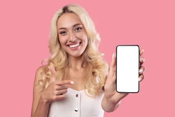 Mujer sosteniendo y apuntando a la pantalla blanca del teléfono inteligente vacío —  Fotos de Stock