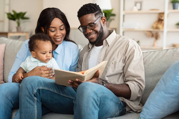 Portret van gelukkig zwart familie lezen boek voor zuigeling — Stockfoto