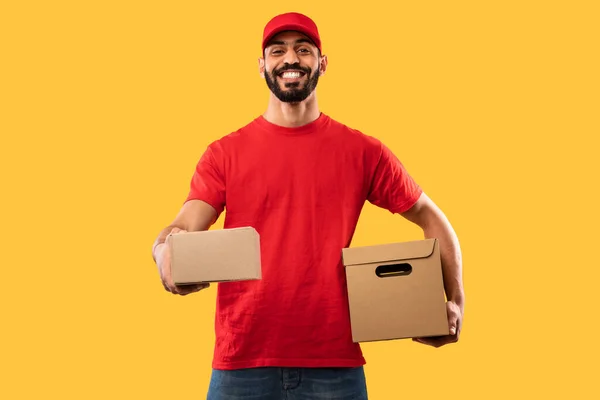 Árabe Courier cara entregando caixas de papelão sobre amarelo estúdio fundo — Fotografia de Stock