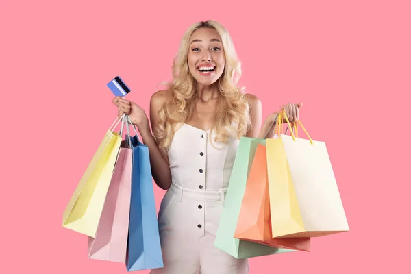 Excitada senhora segurando cartão de crédito carregando sacos de compras — Fotografia de Stock