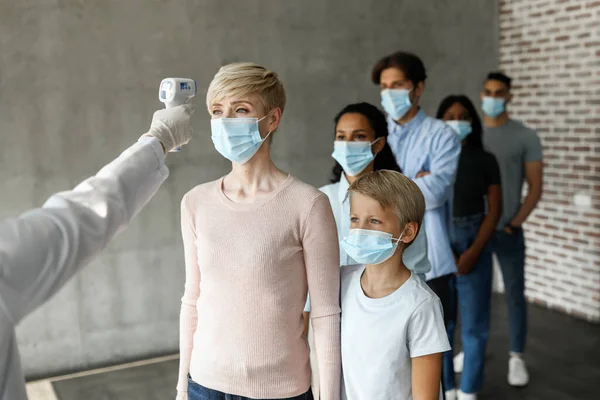 얼굴 마스크를 착용하고 있는 여러 인종의 환자들 이 체온을 재고 있다 — 스톡 사진