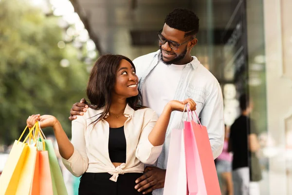 Schönes schwarzes Paar mit Einkaufstüten, die sich gegenseitig anschauen — Stockfoto