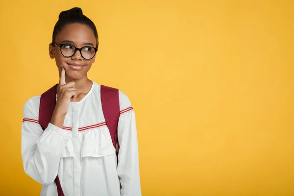 Pensive smart teen afro american female pupil in glasses with backpack thinks and looks at empty space — Stock Photo, Image