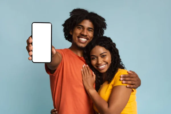 Älskande svart par omfamnar och visar smartphone, mockup — Stockfoto