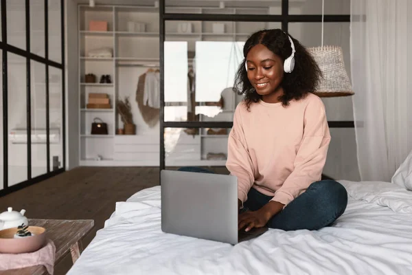 African Kobieta Korzystanie Laptop noszenie słuchawki pracy online w domu — Zdjęcie stockowe