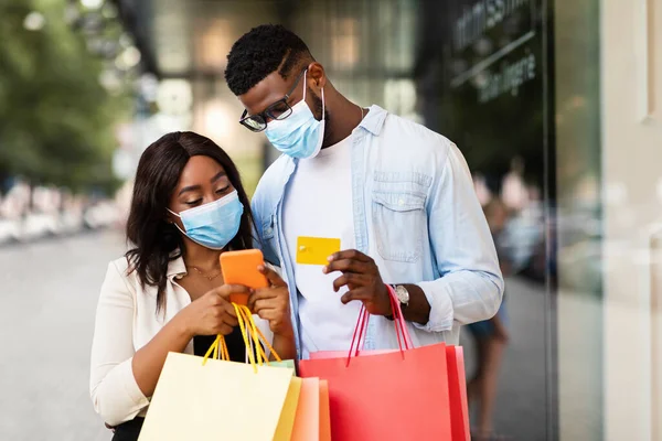 Akıllı telefon bankası kredi kartı kullanan maskeli Afro çift