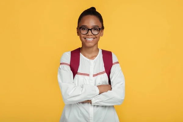 Cheerful confident calm cute adolescent african american student girl in glasses with backpack with crossed arms — Stock Photo, Image