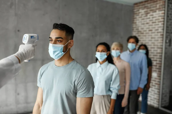 Multiracial men and women in face masks checking body temperature — Stock Photo, Image