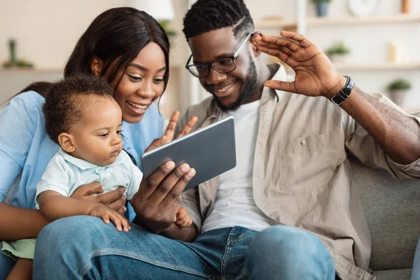 Черная семья имеет видео-звонок с помощью планшета размахивая руками — стоковое фото
