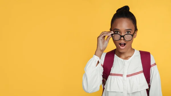 Šokovaný pozitivní mladé černošky dívka žák sundat brýle s otevřenými ústy a při pohledu na kameru — Stock fotografie
