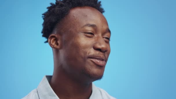 Interview-Konzept. Nahaufnahme Porträt eines jungen positiven afrikanisch-amerikanischen Typen, der mit seinem Gesprächspartner spricht, blauer Hintergrund — Stockvideo