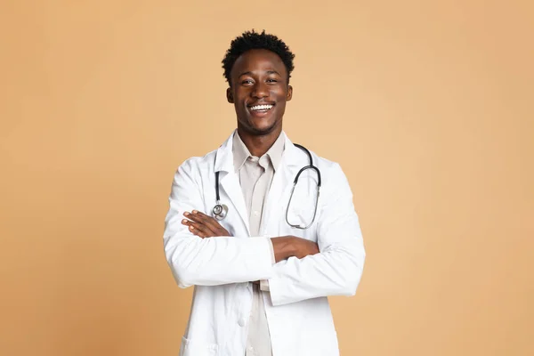 Retrato del doctor negro confiado en uniforme posando sobre fondo beige —  Fotos de Stock