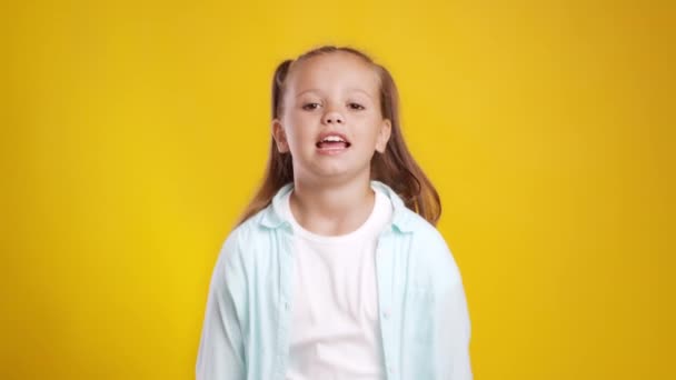 O quê? Menina feliz emocional com dois rabos de cavalo desfrutando de sucesso, celebrando a realização, fundo de estúdio laranja — Vídeo de Stock