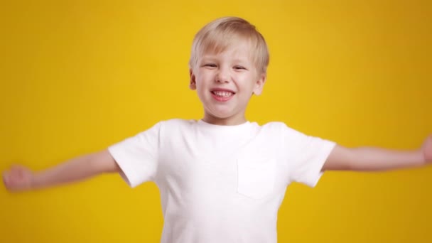 Хораї. Чарівний маленький блондинка махає руками і кричить щасливо, насолоджуючись успіхом або сюрпризом, помаранчевий фон — стокове відео