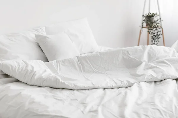 Низкая несделанная кровать, удобная подушка, белое постельное белье ни с кем — стоковое фото
