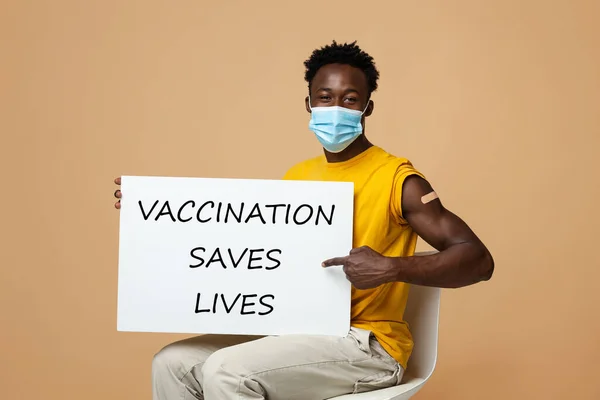 Jovem afro-americano cara segurando Placard com vacinação salva vida motivacional inscrição — Fotografia de Stock