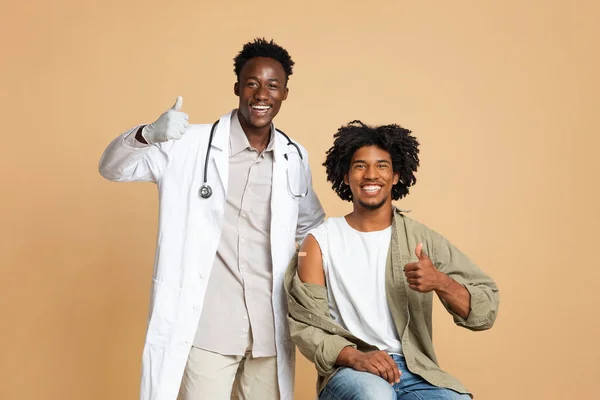 Médico afroamericano y paciente masculino mostrando pulgares hacia arriba después de la vacunación exitosa —  Fotos de Stock