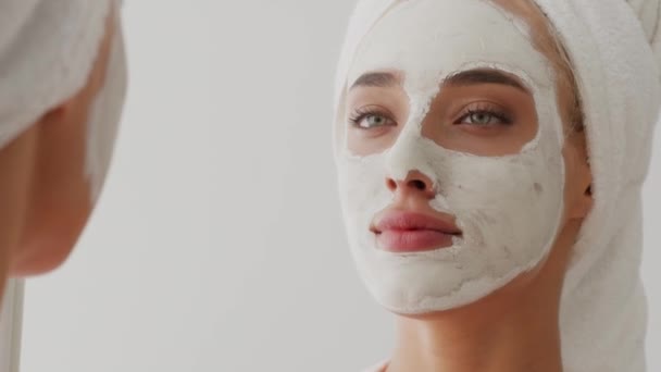 Young Beautiful Woman With Applied Clay Mask On Face Looking In Mirror — Stock Video