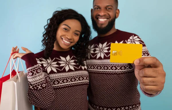 Χριστουγεννιάτικα ψώνια. Ενθουσιασμένο ζευγάρι Αφροαμερικανών με τσάντες για ψώνια και πιστωτική κάρτα, μπλε φόντο — Φωτογραφία Αρχείου