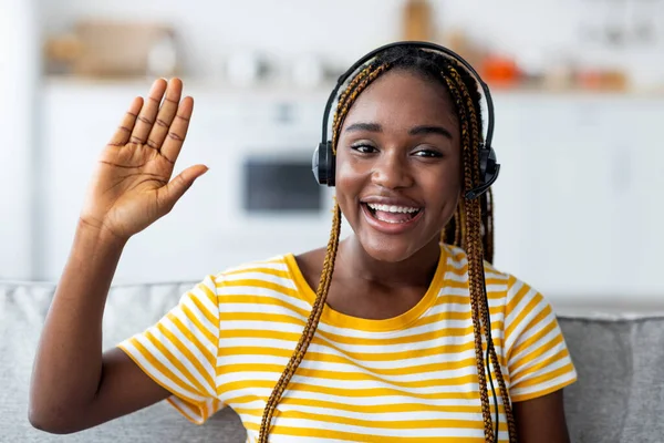 Primer plano de la alegre mujer negra con auriculares saludando a la cámara —  Fotos de Stock
