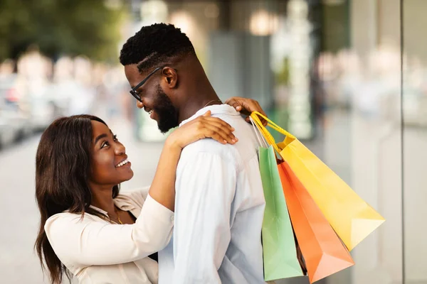 Gelukkig Afro-Amerikaans paar knuffelen en houden boodschappentassen — Stockfoto