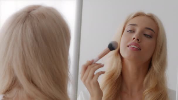 Gör upp. Vacker blond kvinna tittar på spegel och använda kosmetisk borste — Stockvideo