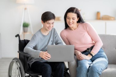 Evde eğitim. Tekerlekli sandalyedeki engelli çocuk annesiyle birlikte evde öğreniyor.